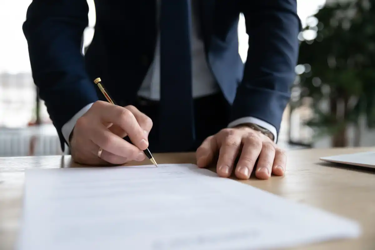 patron en costume de bureau mettre la signature sur le contrat de rémunération commerciaux